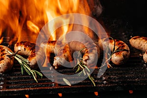 Grilled sausage bratwursts cooking on flaming grill BBQ grill sizzling over flaming hot coals. steel grilled meat. Long banner