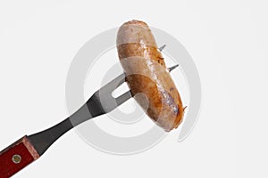 Grilled sausage on a carving fork isolated on white background