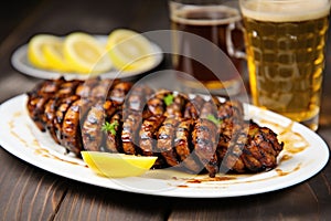 grilled sausage links on a plate next to a filled lager glass