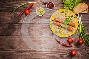 Grilled sausage with pasta, slices of bread, herbs and cherry tomatoes. Top view. On a wooden rustic brown background