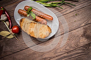 Grilled sausage with pasta, slices of bread, herbs and cherry tomatoes. Top view. On a wooden rustic brown background. Close-up