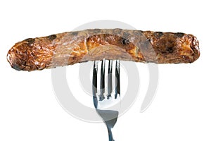 Grilled sausage pierced on a fork, isolated on white