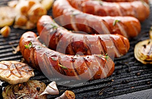 Grilled sausages with the addition of herbs and vegetables on the grill plate, outdoor, close-up