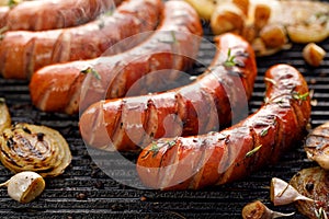 Grilled sausages with the addition of herbs and vegetables on the grill plate, outdoor, close-up