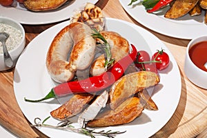 Grilled sausages with baked potatoes, cherry tomatoes and herbs