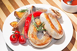 Grilled sausages with baked potatoes, cherry tomatoes and herbs