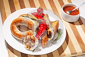 Grilled sausages with baked potatoes, cherry tomatoes and herbs