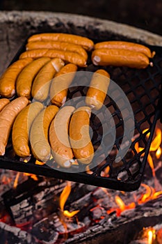 Grilled sausages on the black grate above the fire