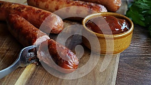 Grilled sausages Bockwurst on a wooden board. Break and pricked sausage with a fork. Close up
