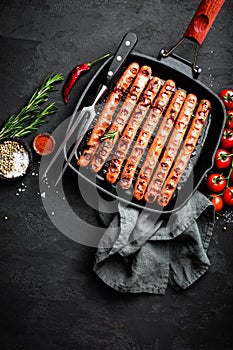 Grilled sausages bratwurst in grill frying-pan on black background. Top view. Traditional German cuisine