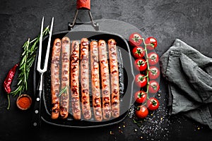 Grilled sausages bratwurst in grill frying-pan on black background. Top view. Traditional German cuisine