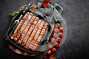 Grilled sausages bratwurst in grill frying-pan on black background. Top view. Traditional German cuisine