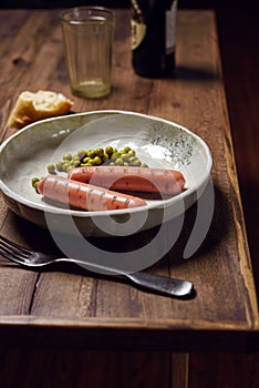 Grilled sausages with green peas served with dark beer and artisan bread