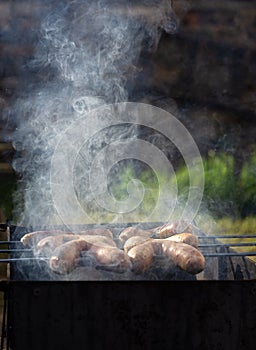 Grilled sausages on grill with smoke