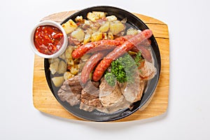 Grilled sausages with potatoes, and roasted meat on a grill pan