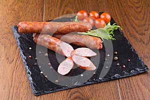 Grilled sausages on slate plate with cherry tomatoes and grren