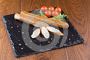 Grilled sausages on slate plate with cherry tomatoes and grren