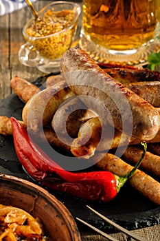 Grilled sausages and stewed cabbage with a mug of beer on a wood