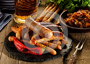 Grilled sausages and stewed cabbage with a mug of beer on a wood