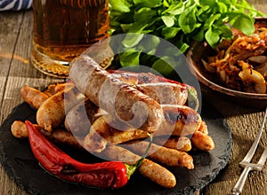 Grilled sausages and stewed cabbage with a mug of beer on a wood