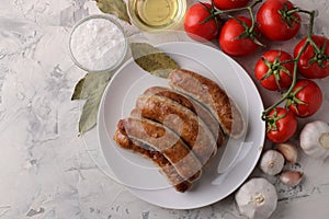 Grilled sausages with tomatoes, sunflower oil and garlic on a light background. top view