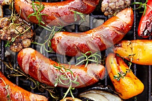 Grilled sausages and vegetables with addition spices and fresh herbs on a grill plate