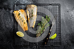 Grilled sea bass fillet with lime and thyme. Black background. Top view