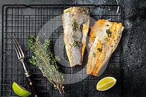 Grilled sea bass fillet with lime and thyme. Black background. Top view