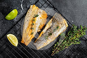 Grilled sea bass fillet with lime and thyme. Black background. Top view