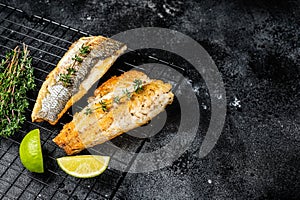 Grilled sea bass fillet with lime and thyme. Black background. Top view. Copy space