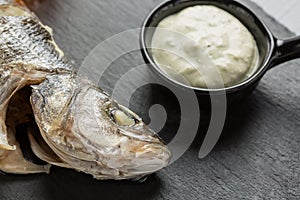 Grilled sea bass with a sauce on black slate plate close up