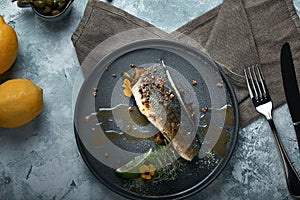Grilled seabass with eggplant and lime. Horizontal top view, top shot. Copy space, gray concrete marble background, soft