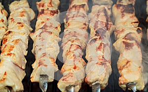 Grilled shish kebab on metal skewer. Chef hands cooking roasted meat barbecue with lots of smoke.