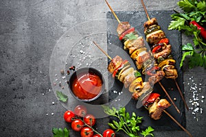 Grilled shish kebab with vegetables on black.