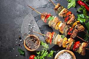 Grilled shish kebab with vegetables on black.