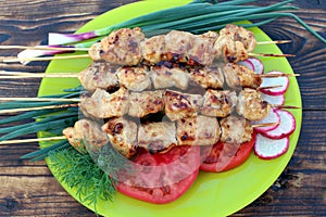 Grilled shish kebab with vegetables is on the plate.