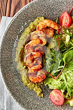 Grilled shrimps with pesto, mix of salads and tomatoes