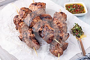 Grilled sirloin tips or beef meat skewers with chimichurri sauce, on wooden tray, horizontal