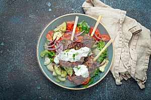 Grilled skewer meat beef kebabs on sticks served with fresh vegetables salad on plate on rustic concrete background from