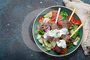 Grilled skewer meat beef kebabs on sticks served with fresh vegetables salad on plate on rustic concrete background from