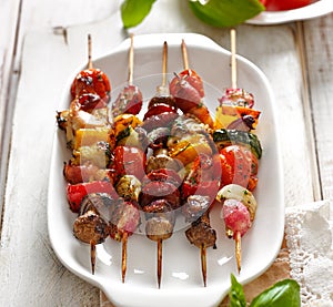 Grilled skewers of vegetables and meat in a herb marinade on white plate