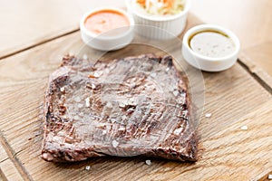 Grilled Skirt Steak with Pickled cabbage and two sauces. Serving on a wooden Board. Barbecue restaurant menu, a series