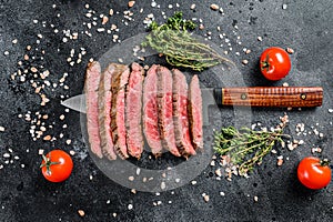 Grilled and sliced flat iron rare steak. Marble beef meat. Black background. Top view