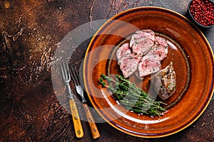 Grilled and sliced lamb fillet meat steak on a plate. Dark background. Top view. Copy space
