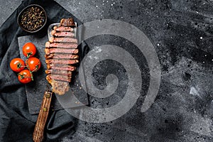 Grilled sliced sirloin steak on a meat cleaver. Black background. Top view. Copy space