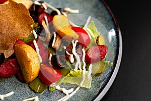 Grilled smoked sausages and baked potatoes on a gray plate, decorated with cherry tomatoes and Chinese cabbage leaves