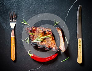Grilled spareribs on slate plate with cutlery