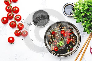 Grilled spicy eggplant with hot red chili peppers, soy sauce, garlic and sesame seeds in asian style, white table background, top