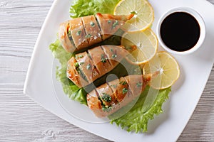 Grilled squid on a plate with sauce. horizontal top view closeup