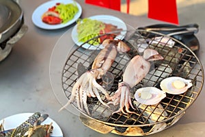 Grilled squid and scallops on mesh grill, with glimpse of street vendor's bustling seaside stall